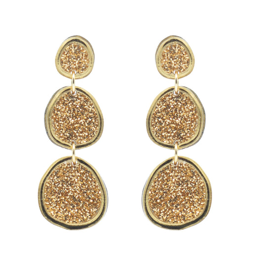 Shimmering gold statement earrings on white background