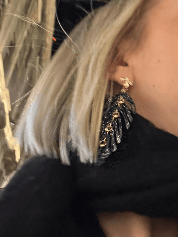 Close up model wearing black statement earrings