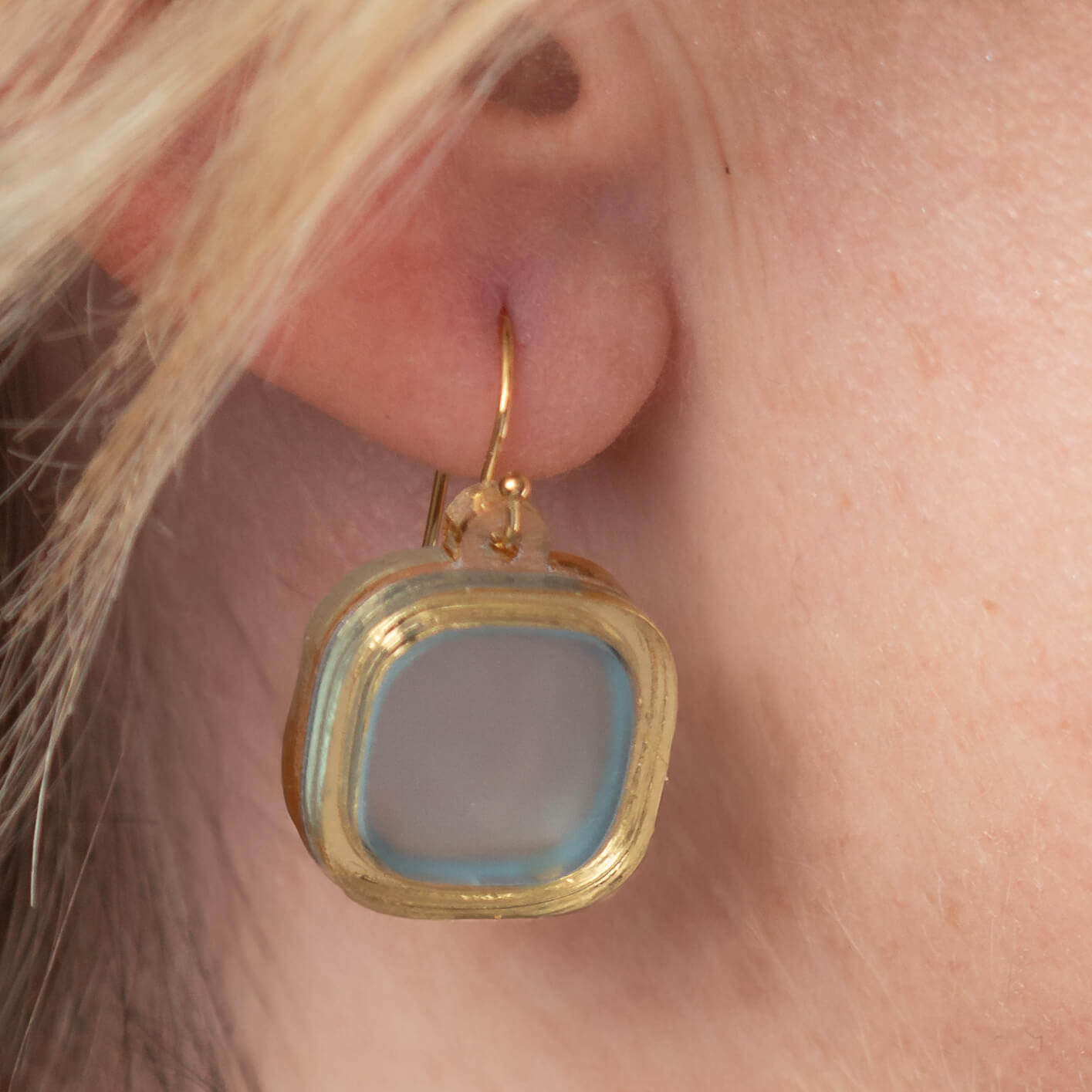 Close-up of model’s ear wearing frosted small wire earrings in arctic blue