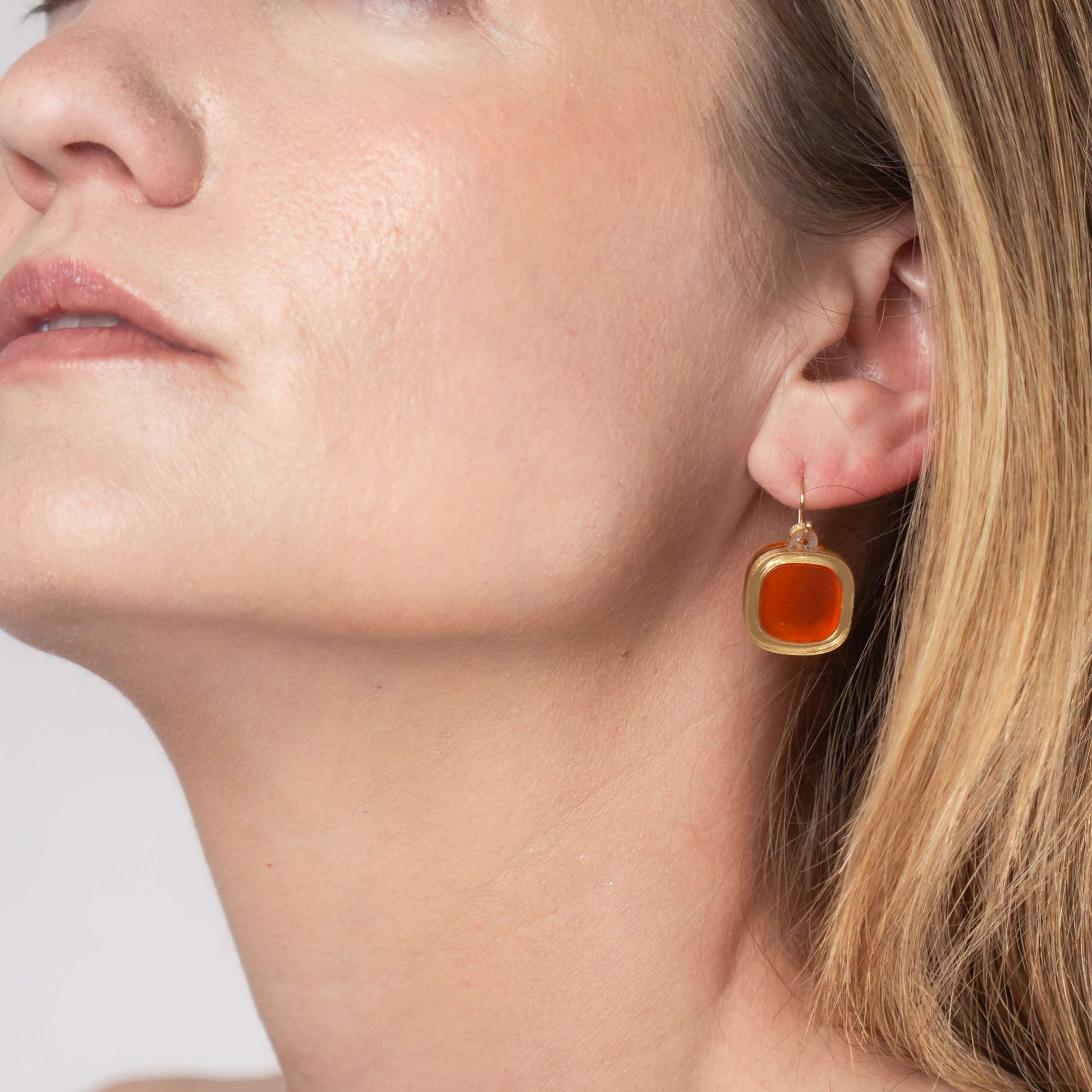Model wearing frosted small wire earrings in mandarin orange