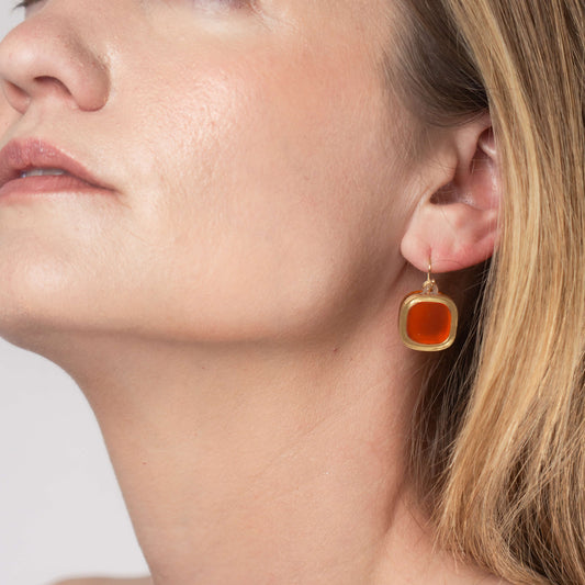 Model wearing frosted small wire earrings in mandarin orange