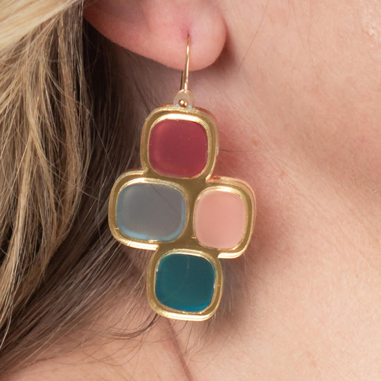 Close-up of model’s ear wearing frosted statement wire earrings in gold and mixed hues