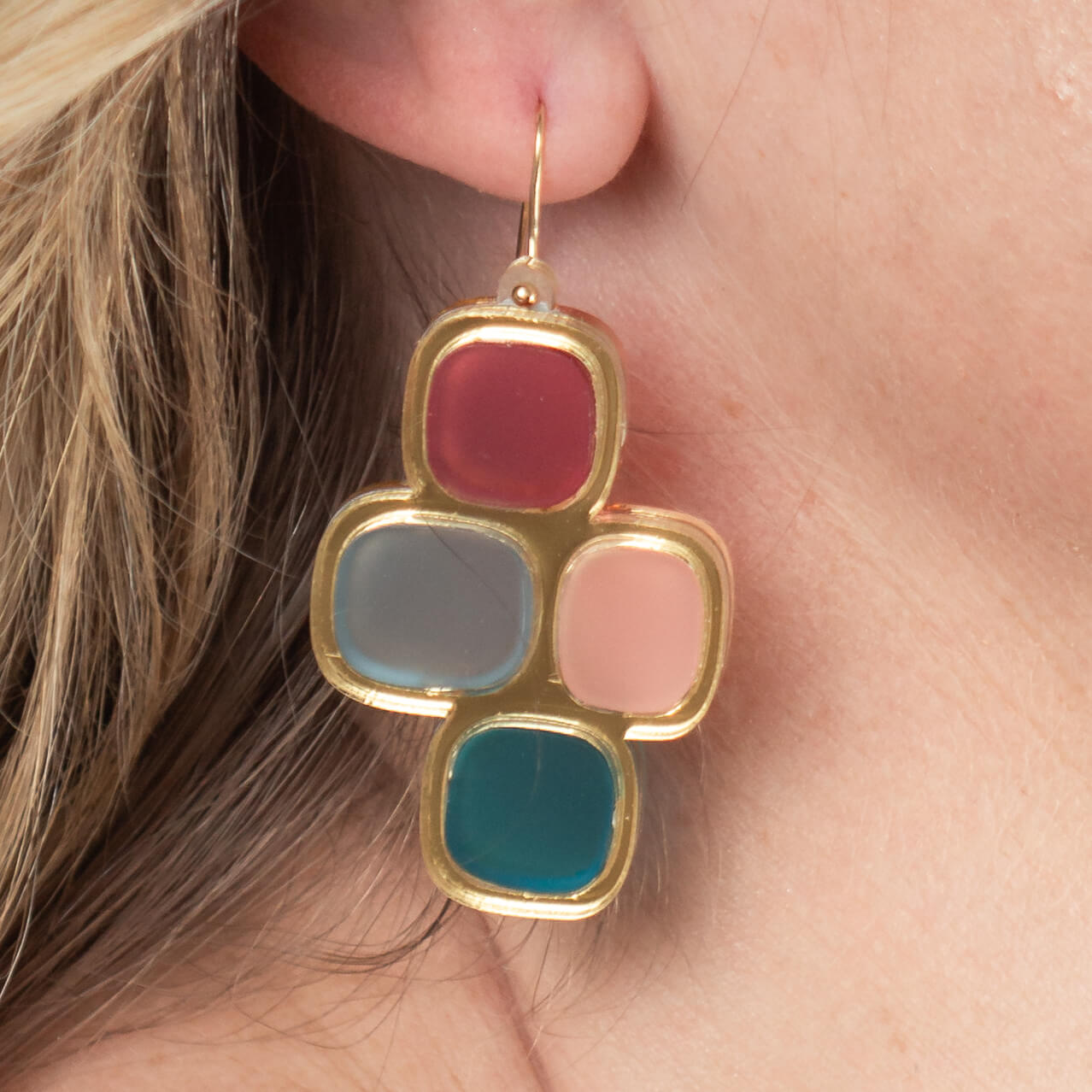 Close-up of model’s ear wearing frosted statement wire earrings in gold and mixed hues