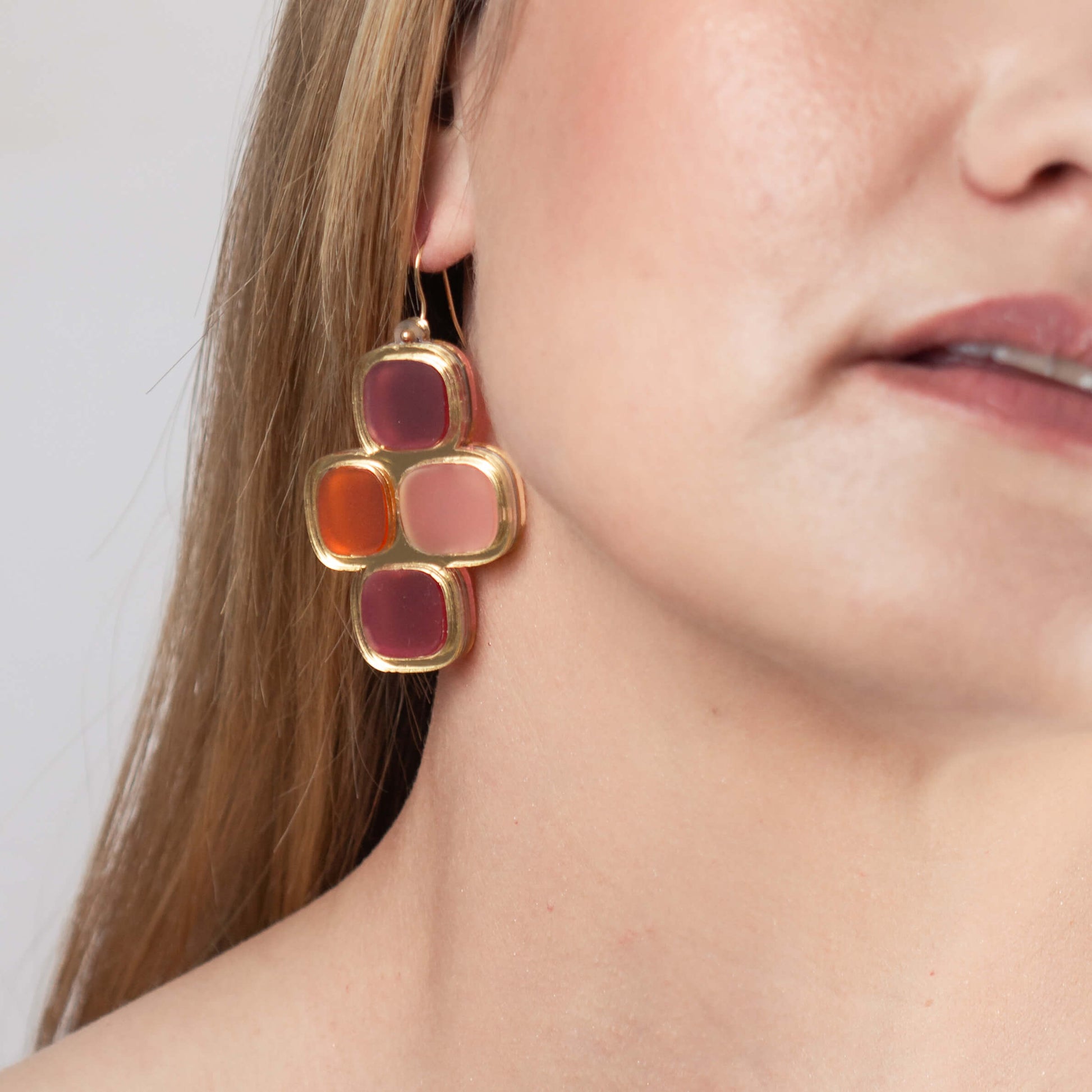 Model wearing frosted statement wire earrings in gold and summer hues