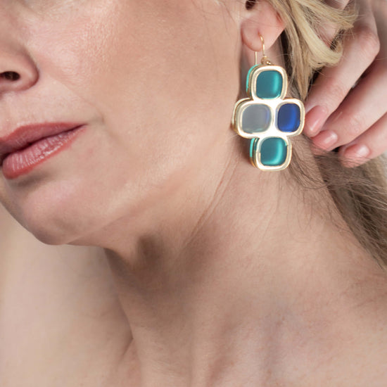 Model wearing frosted statement wire earrings in gold and winter hues