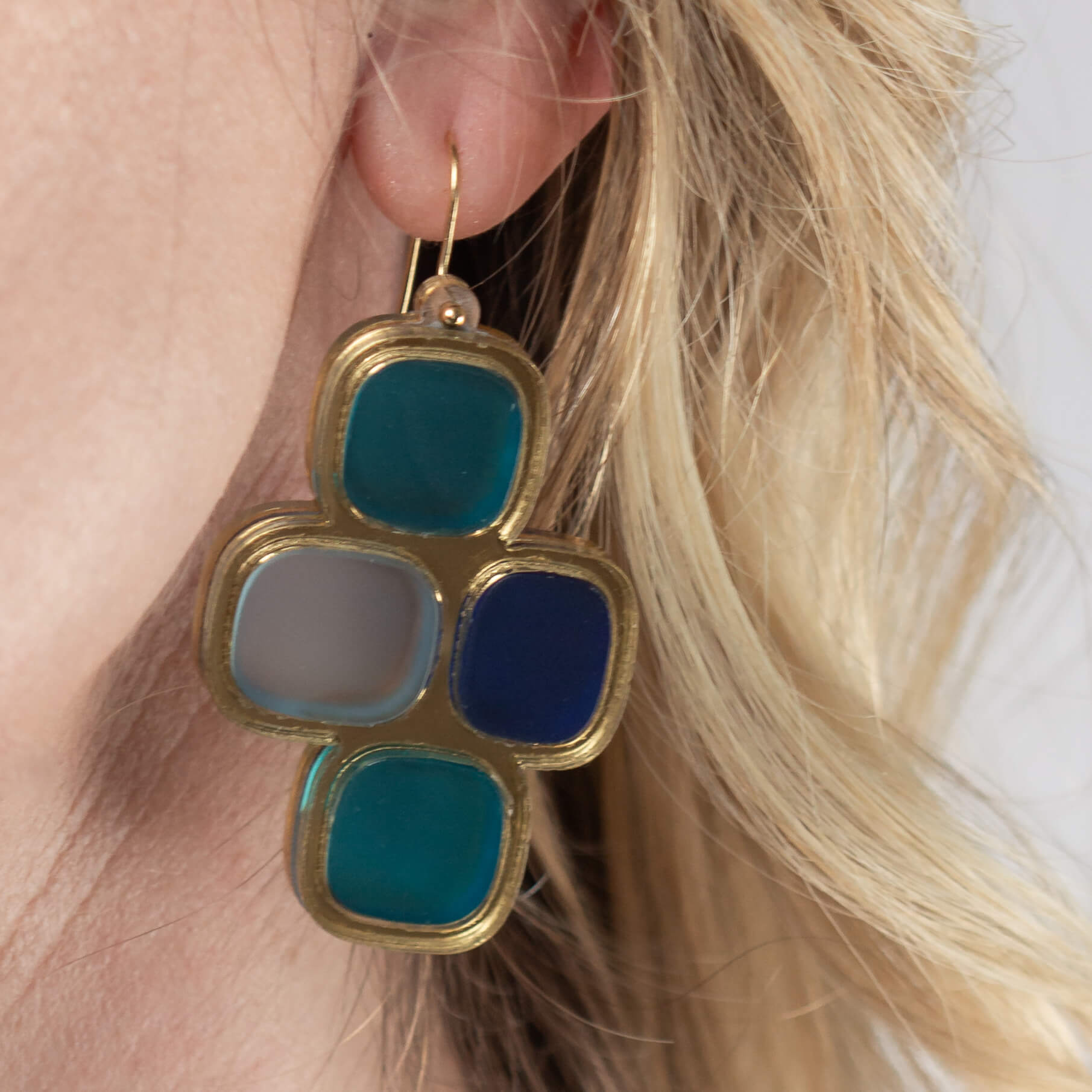 Close-up of model’s ear wearing frosted statement wire earrings in gold and winter hues