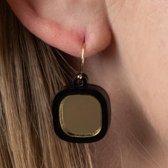 Close-up of model’s ear wearing mirror small wire earrings