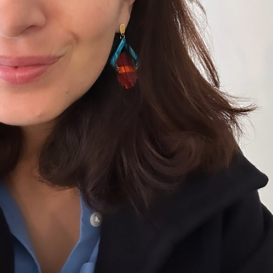 Model wearing turquoise and orange Art Deco Pop earrings with a blue shirt