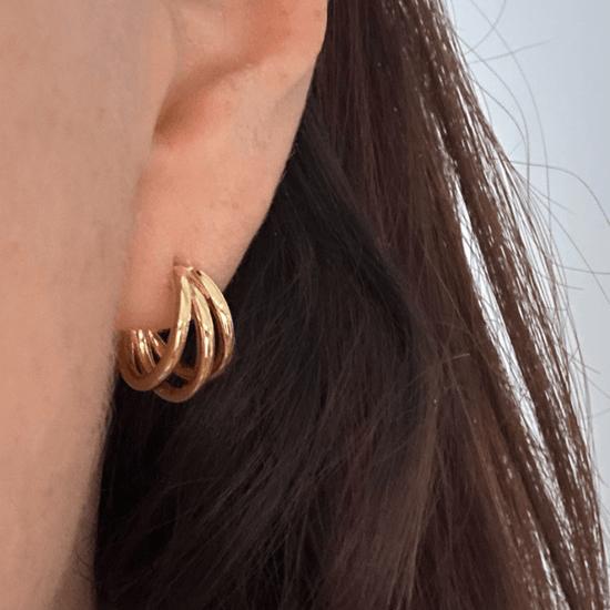 Small gold Trinity hoop earrings with hidden heart detail, close-up
