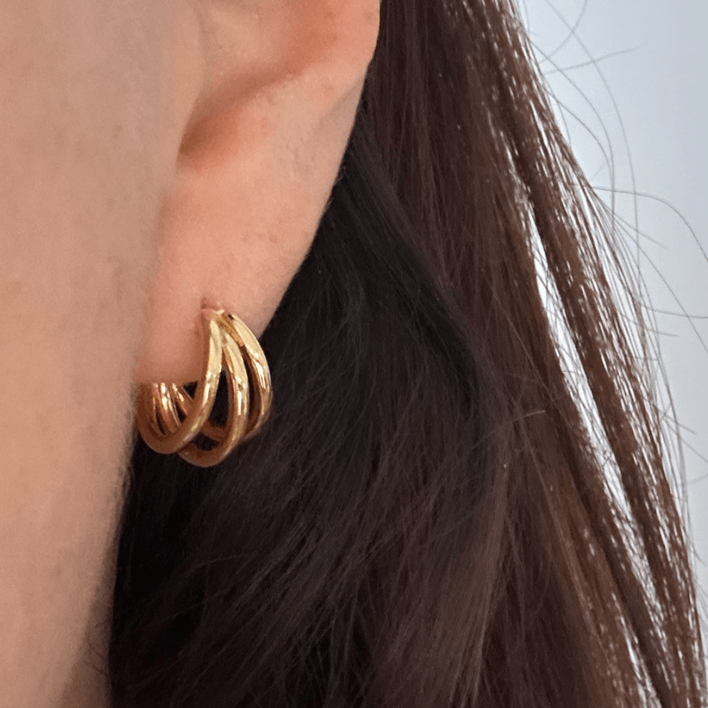 Small gold Trinity hoop earrings with hidden heart detail, close-up