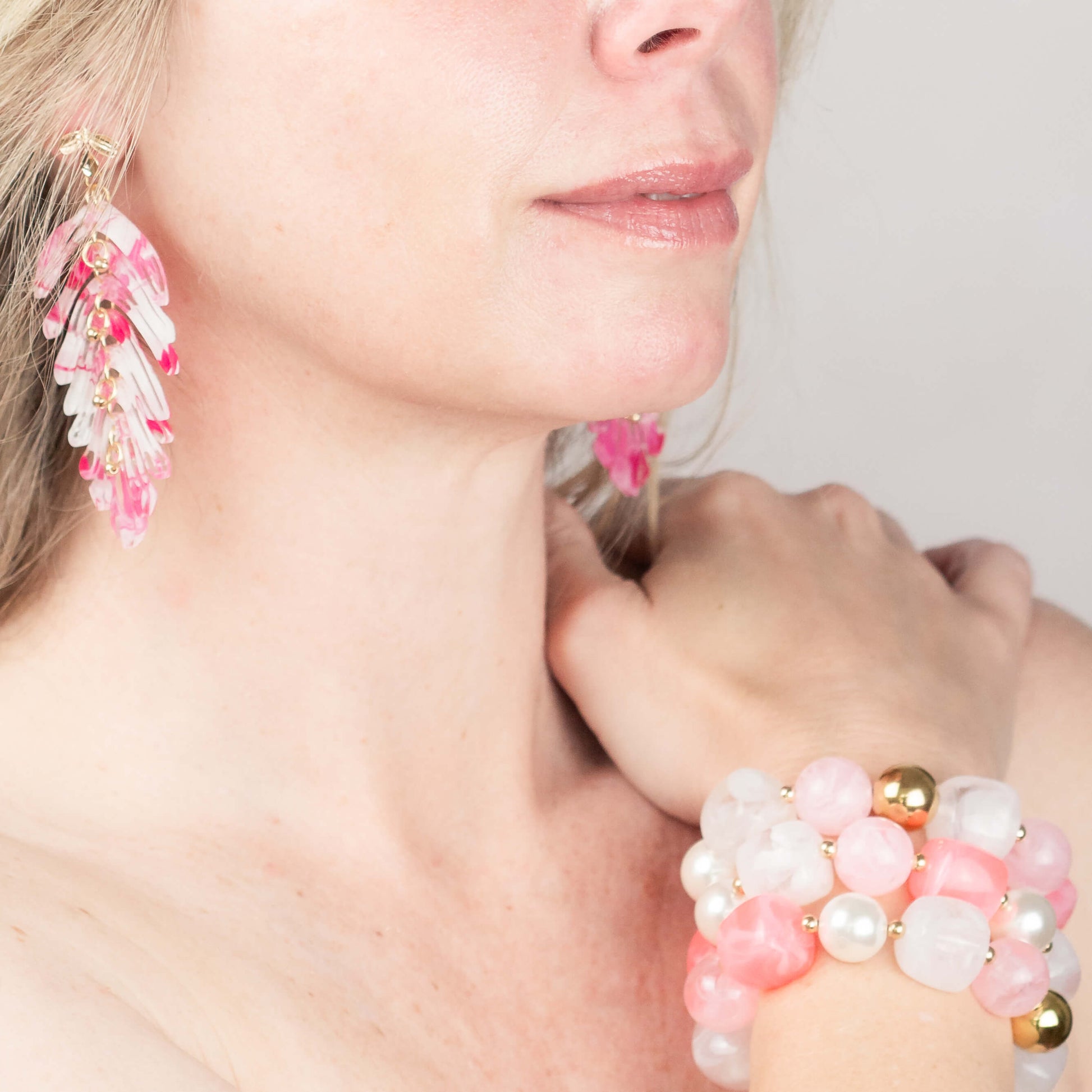 Woman wearing lemonade pink statement beaded bracelet and raspberry pink long leaf earrings, gold plated, Douceur Acidulée collection by Hélène Elisabeth