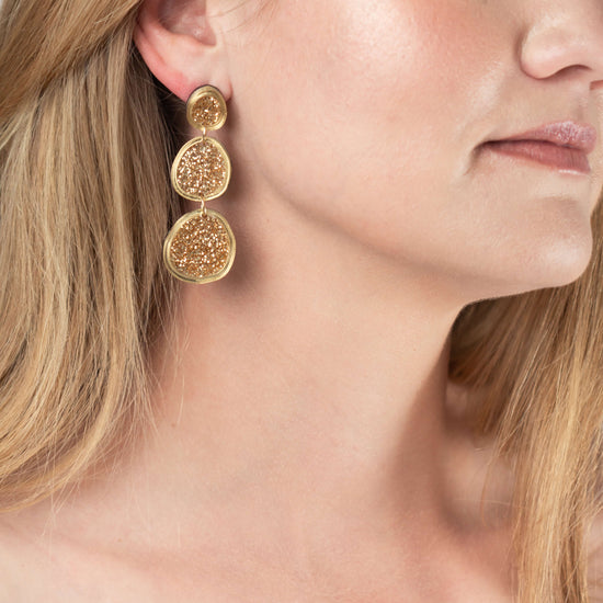 Model wearing shimmering gold statement earrings