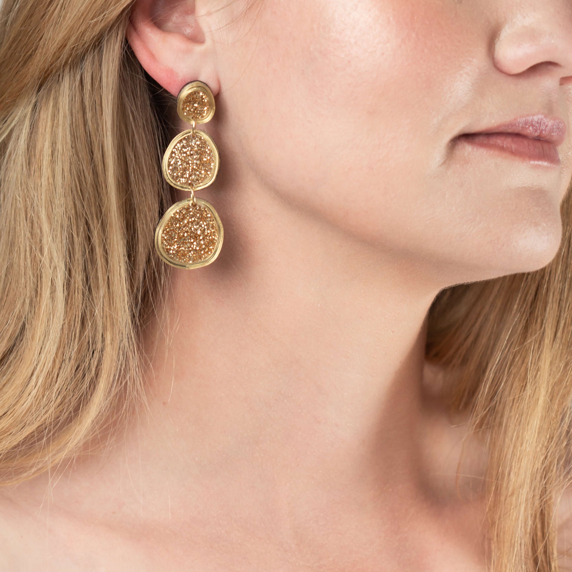 Model wearing shimmering gold statement earrings