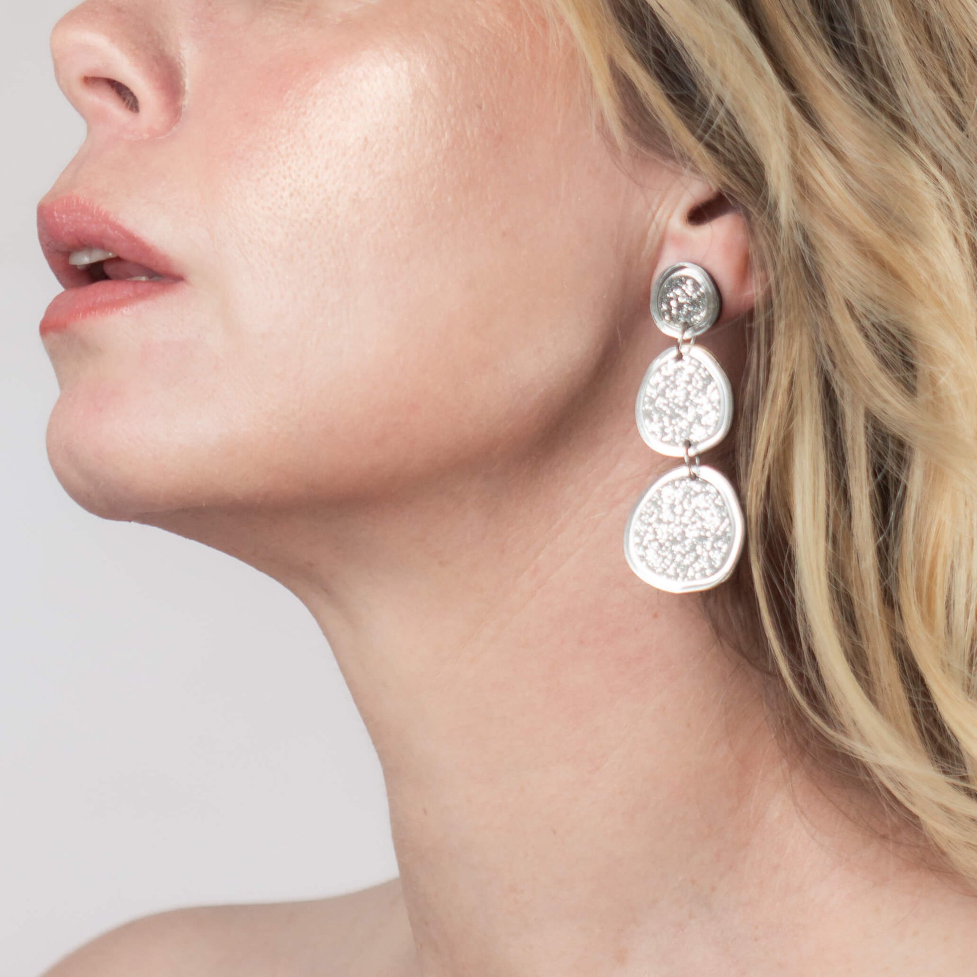 Model wearing shimmering silver statement earrings