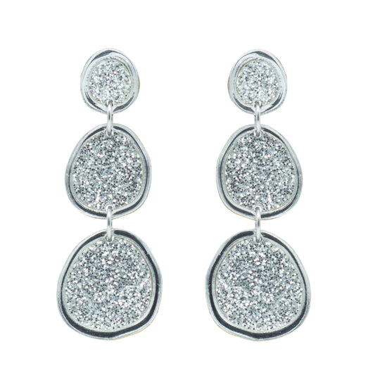 Shimmering silver statement earrings on white background
