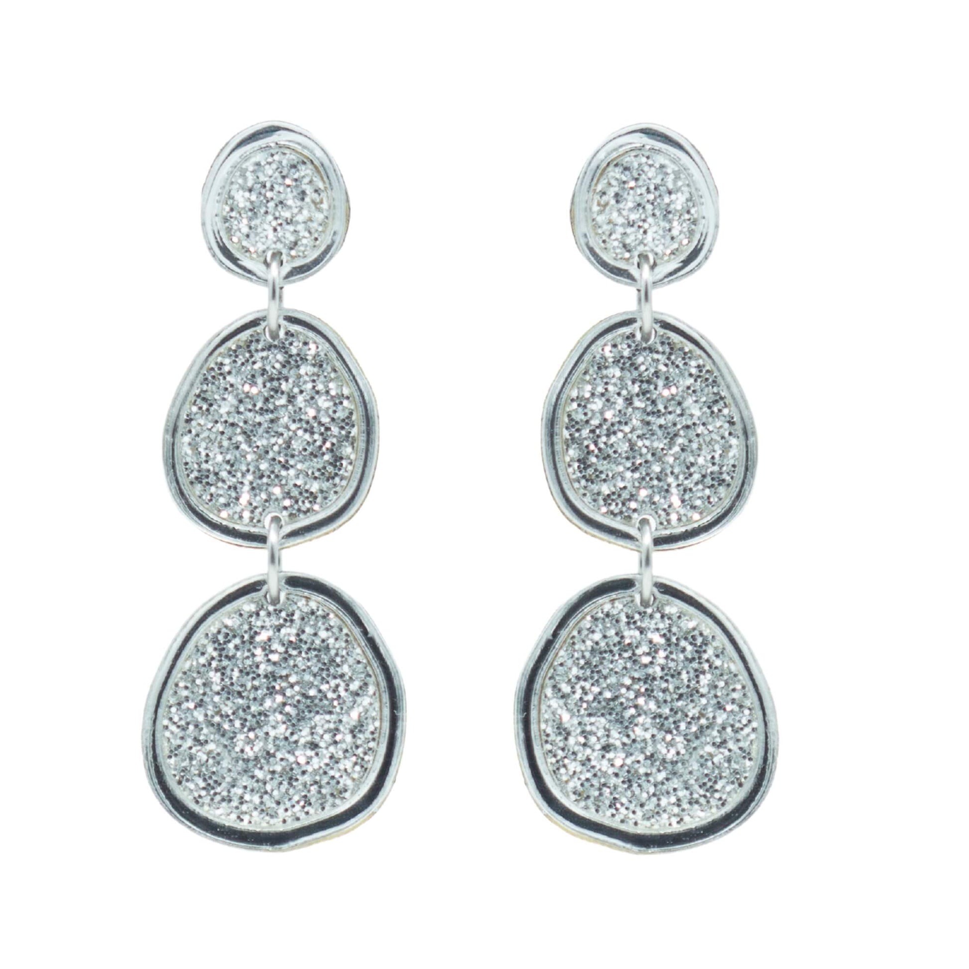 Shimmering silver statement earrings on white background