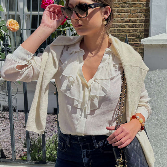 Model wearing matching cream earrings and bracelet.