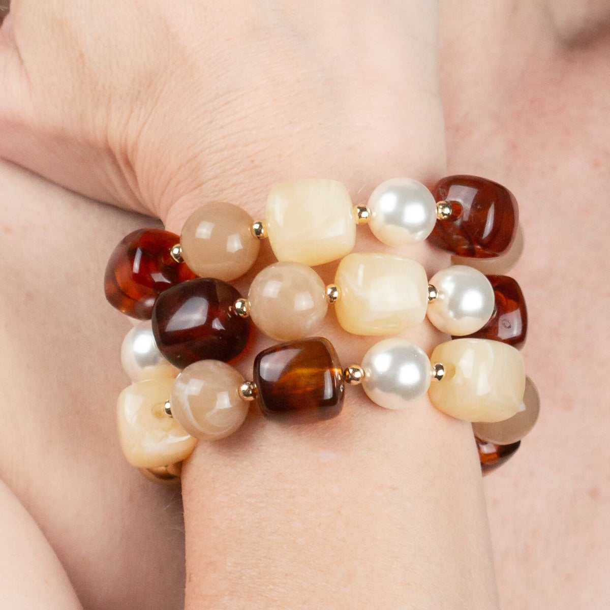 Close-up of the Chestnut Cream Statement Beaded Bracelet worn on the wrist, showing the gold-plated, tortoiseshell, marbled cream and pearl beads in detail.