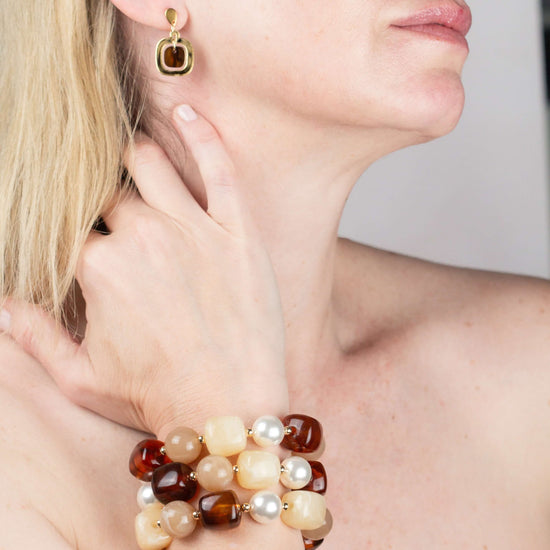 Model wearing a gold and tortoiseshell drop earring with the Chestnut Cream Statement Beaded Bracelet, hand raised to her chin. Matching earrings.