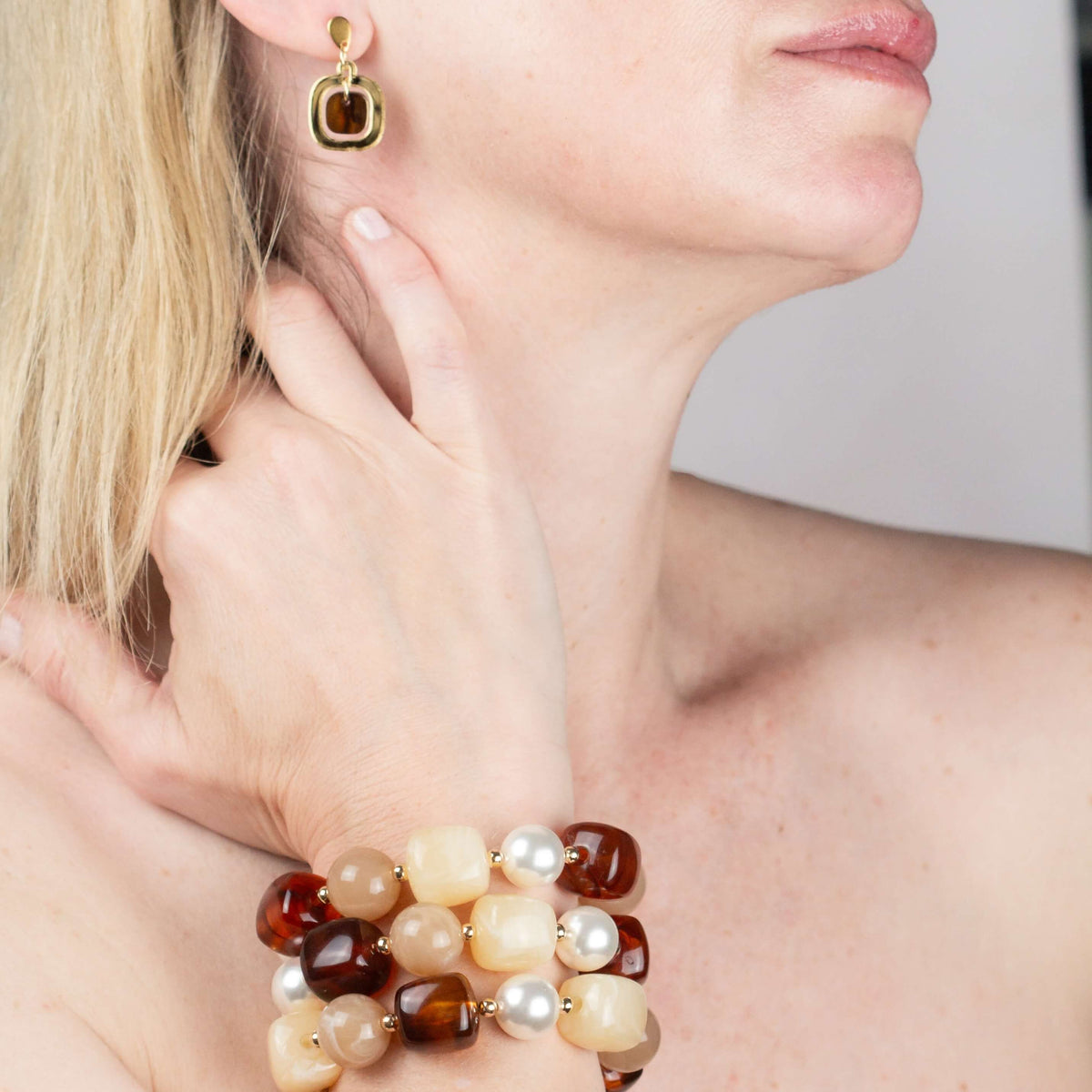 Model wearing a gold and tortoiseshell drop earring with the Chestnut Cream Statement Beaded Bracelet, hand raised to her chin. Matching earrings.