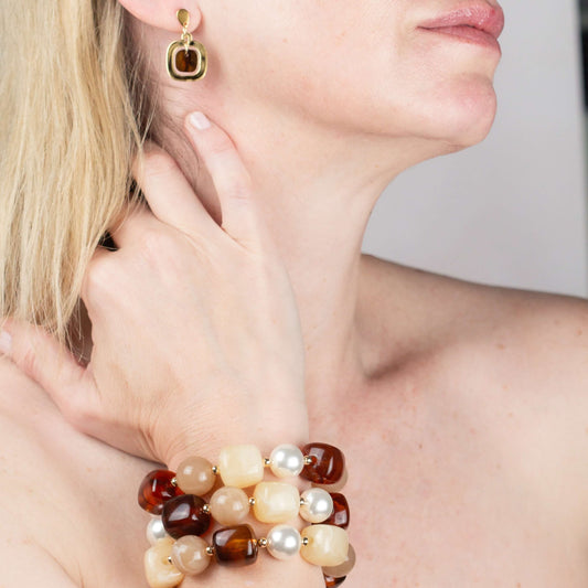 Model wearing a gold and tortoiseshell drop earring with the Chestnut Cream Statement Beaded Bracelet, hand raised to her chin. Matching earrings.